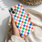A hand holding a colorful phone case with a checkered pattern.