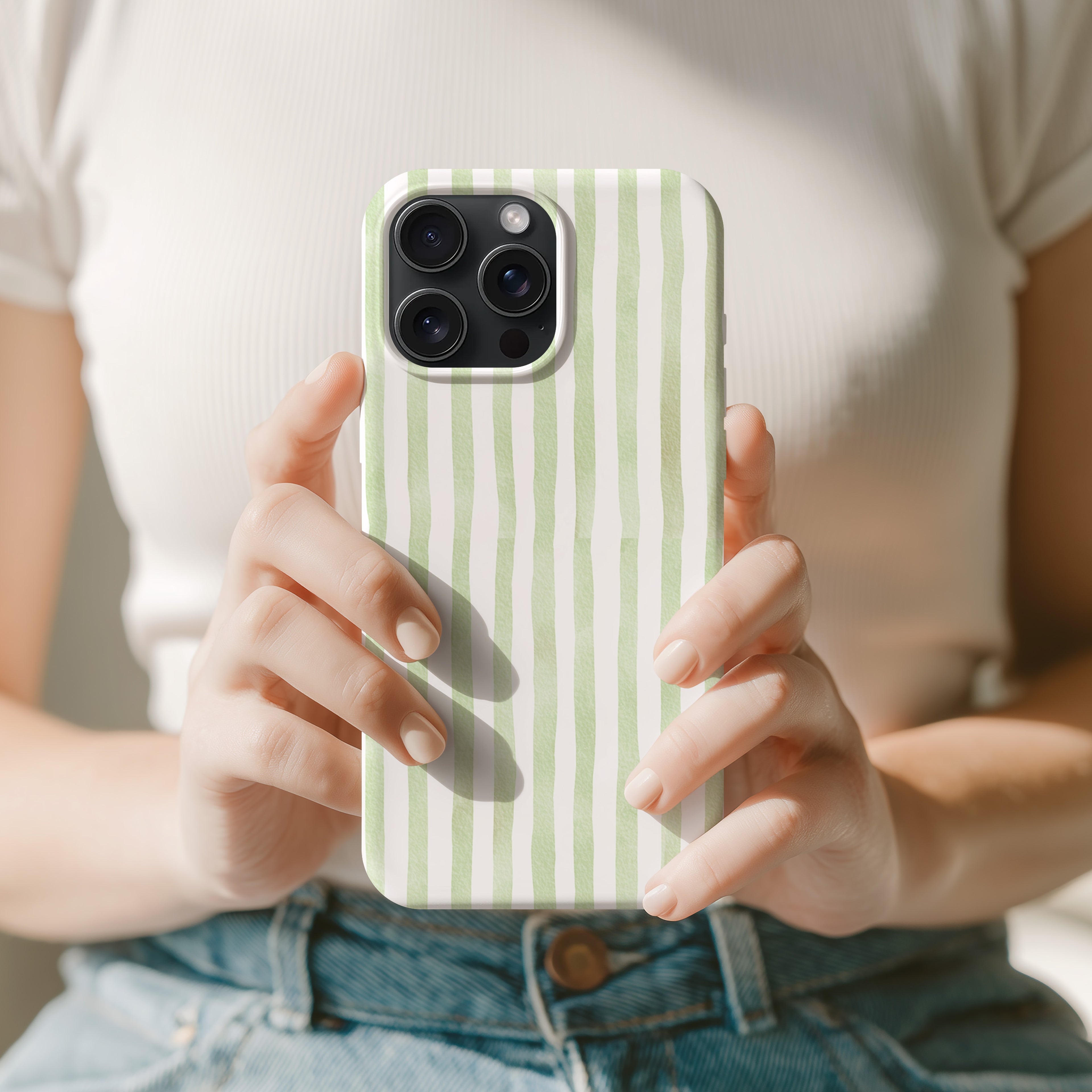 A person is holding a phone with a green and white striped case in front of them.