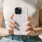 A person is holding a phone with a patterned case featuring pink and blue stars.