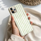 A hand holding a phone case with green and white striped pattern.