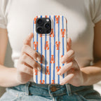 A person is holding a phone case with a striped pattern of blue and white stripes and red lobster illustrations.