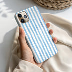 A hand holding a blue and white striped phone case.