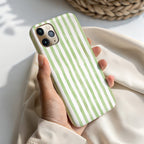 A hand holding a phone case with green and white striped pattern.