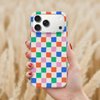 A hand holding a colorful phone case with a checkered pattern.