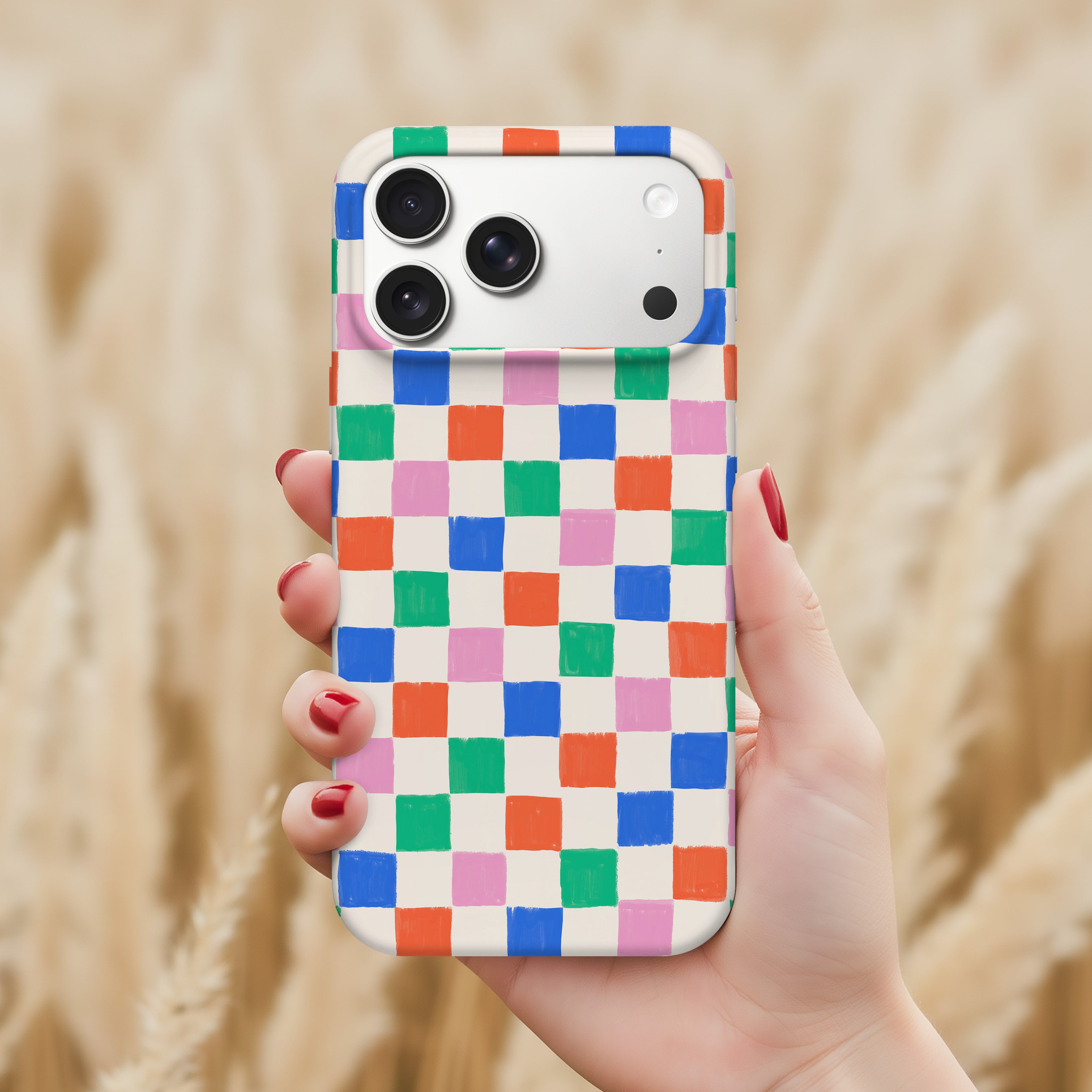 A hand holding a colorful phone case with a checkered pattern.