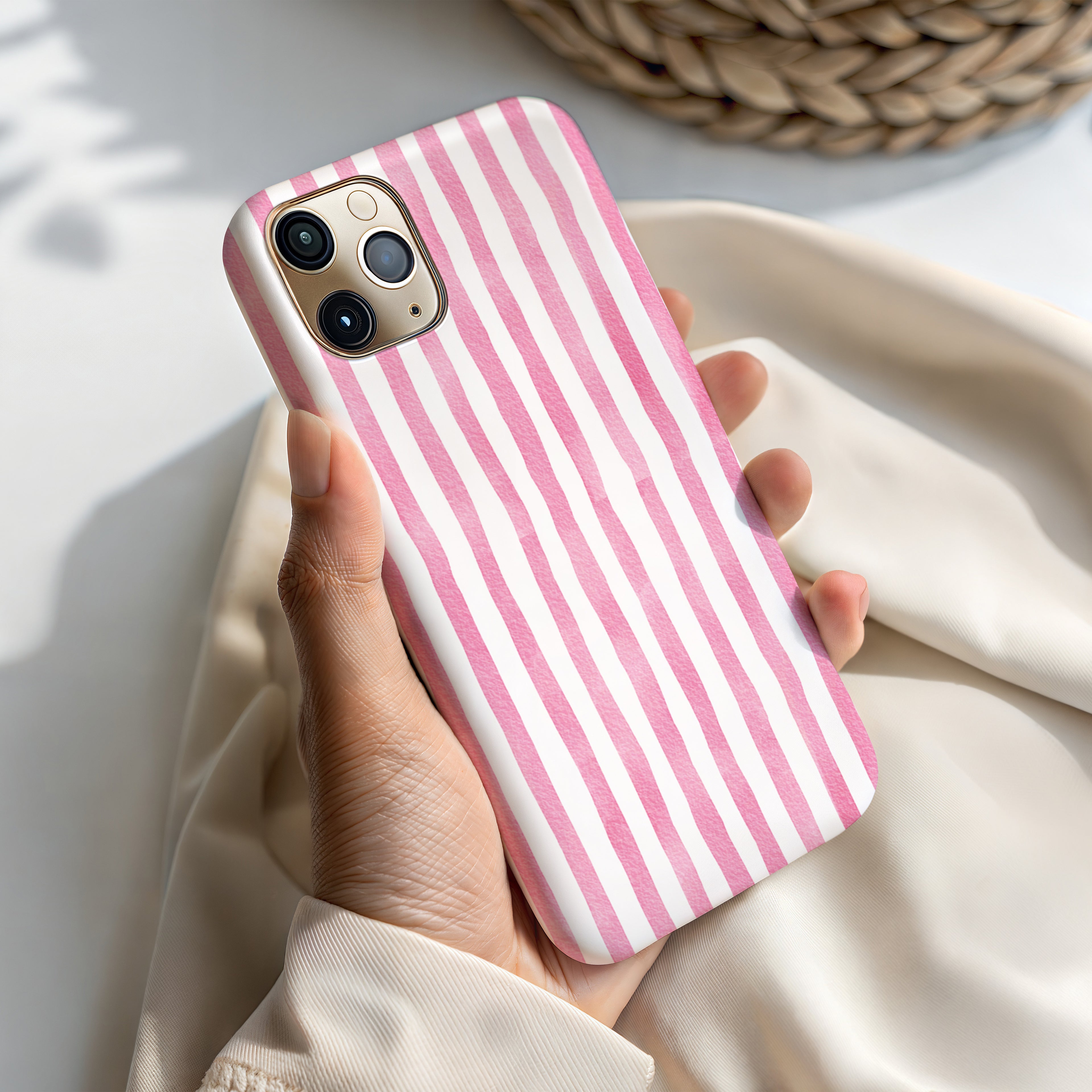 A hand holding a pink and white striped phone case.