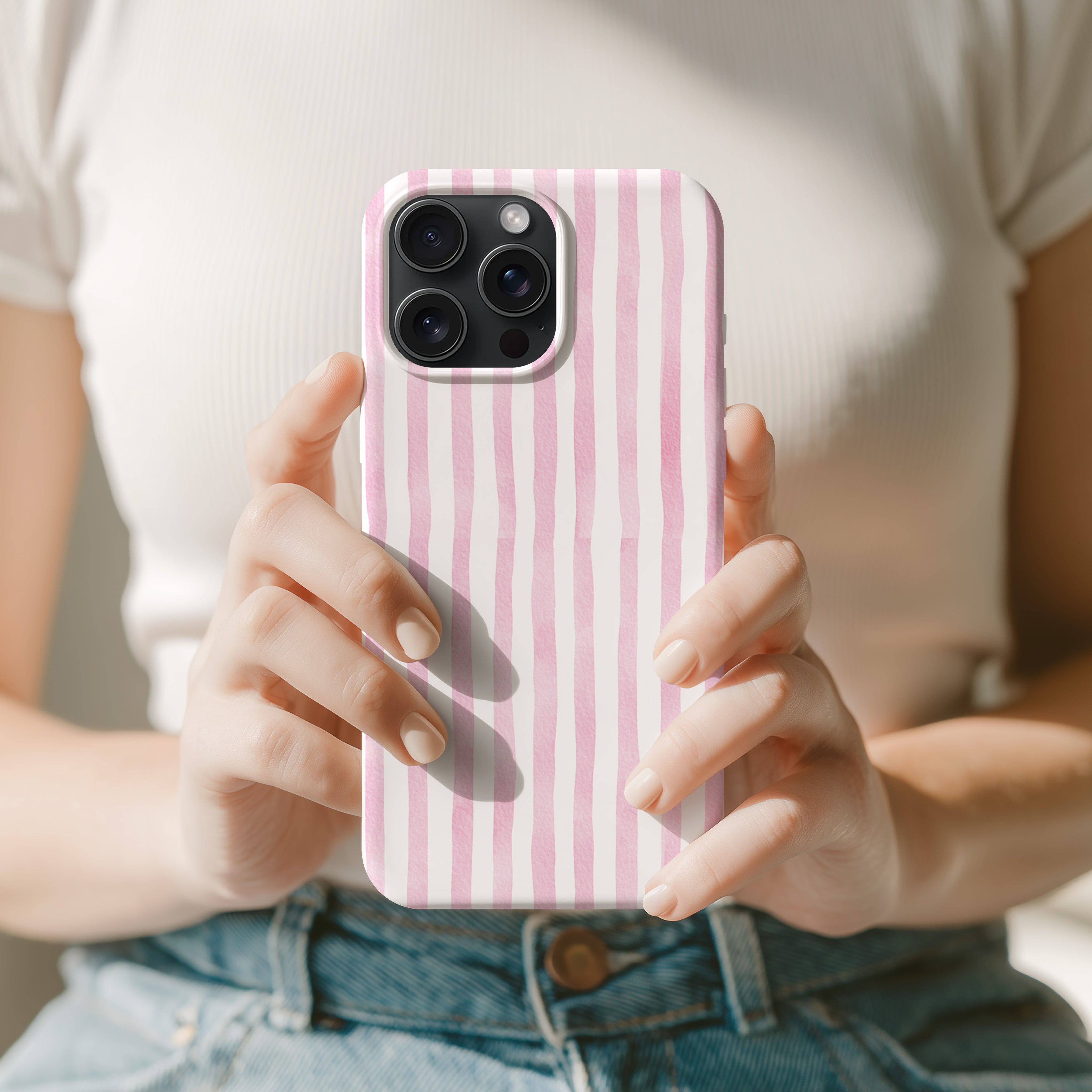 A person is holding a pink and white striped phone case in their hands.