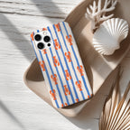 a smartphone case with a striped pattern of blue and orange lines, along with a seashell and some dried leaves on a wooden surface.