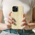 A person is holding a yellow and white striped phone case in their hands.