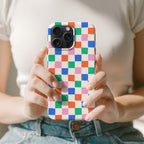 A person is holding a colorful phone case with a checkered pattern.