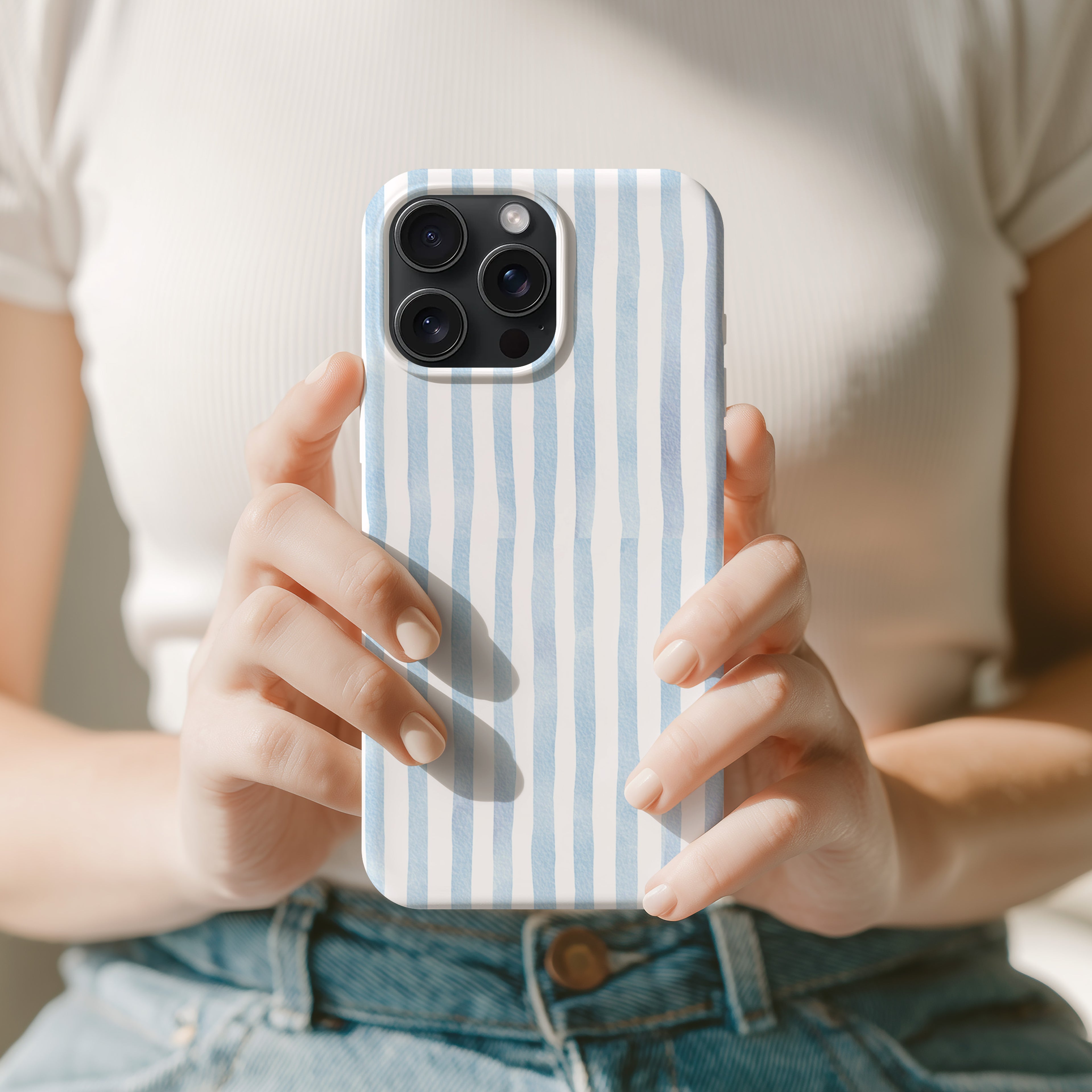 A person is holding a smartphone with a striped case in their hands.