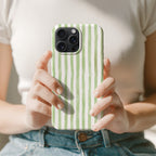 A person is holding a phone with a green and white striped patterned case.