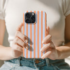 A person is holding a smartphone with a striped pattern on the case.
