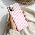 A hand holding a pink and white striped phone case.