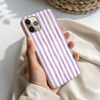 A hand holding a phone case with purple and white striped pattern.