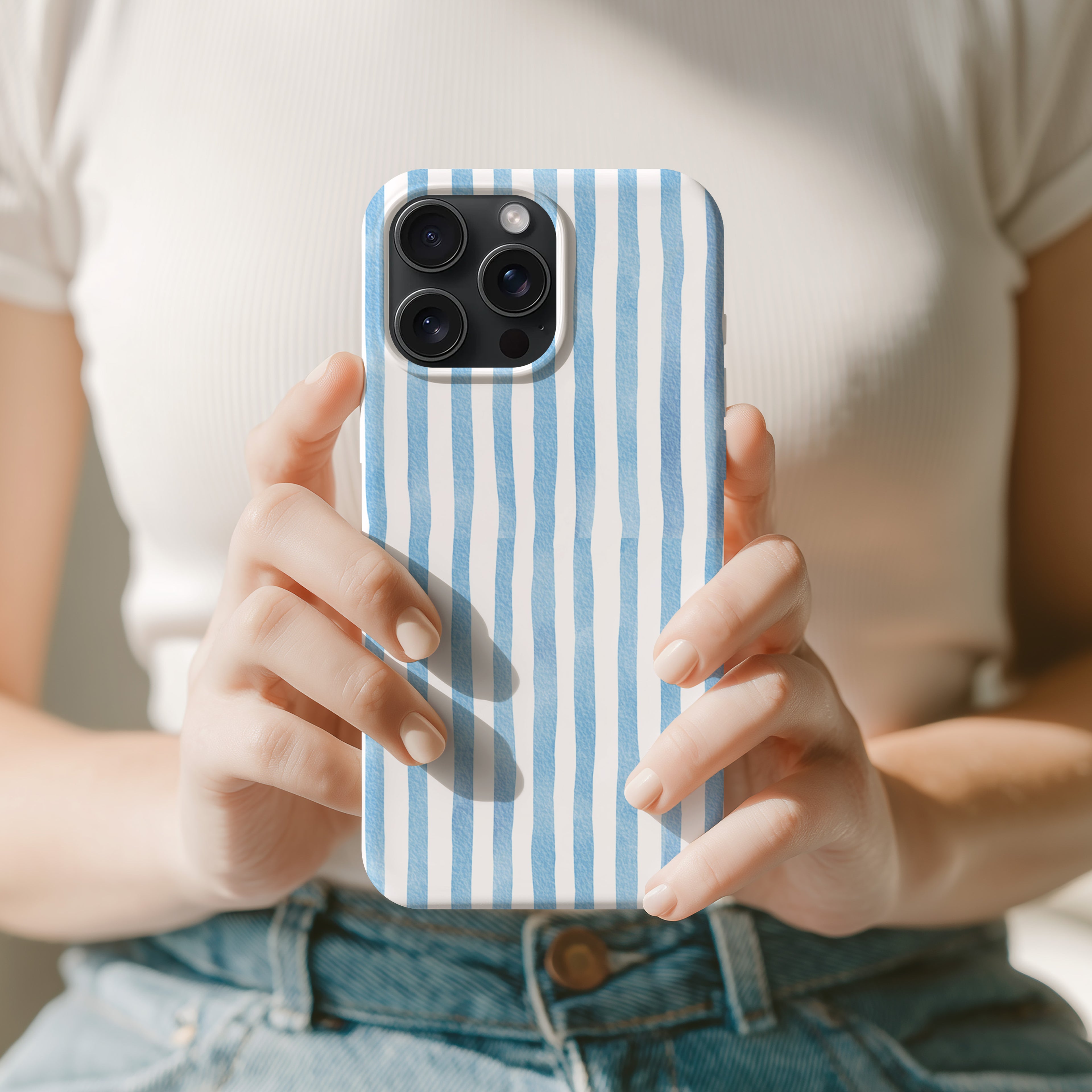 A person is holding a smartphone with a blue and white striped patterned case.